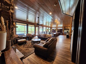 A spacious living area with a high ceiling, large windows, and a fireplace. - Luxury 15BR Cabin w/ Indoor Pool, Theater, Hot Tubs, Sleeps 64 Guests (Sevierville)