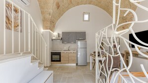 A modern kitchen with stone walls, a dining area, and a staircase.