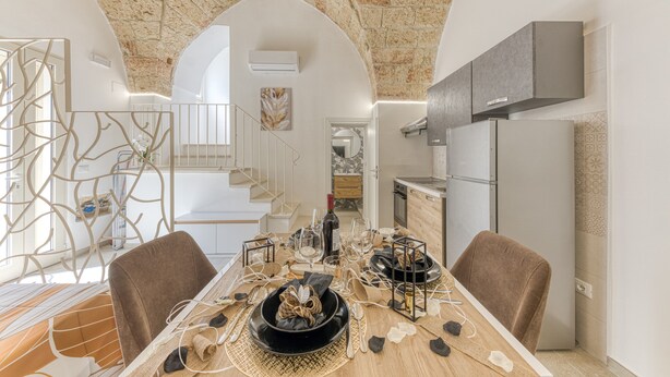 A dining area with a stone ceiling, a staircase, and a kitchen area.