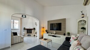 Ein modernes Wohnzimmer mit Kamin, Flachbildfernseher und einer Couch.