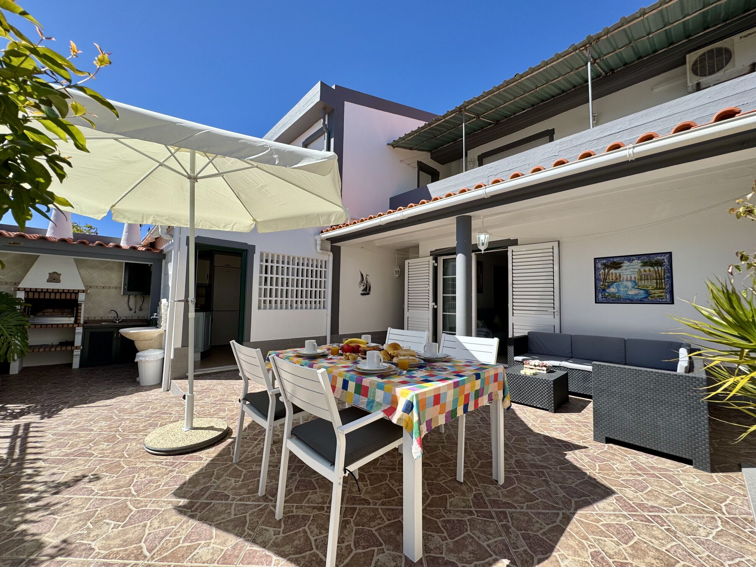 Eine Außenpatio mit Esstisch, Grill und einer Sitzecke.