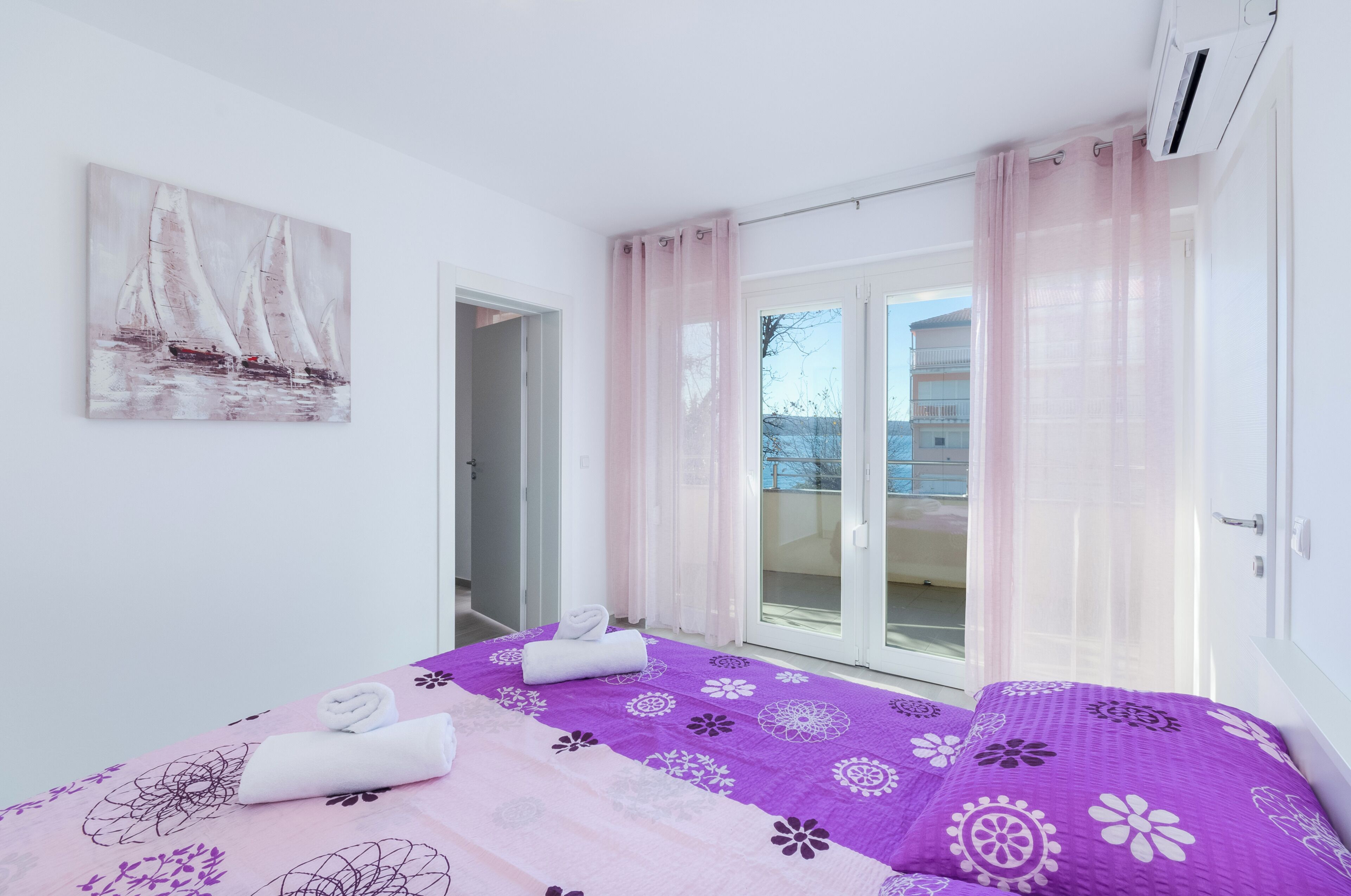 Une chambre avec un lit, un tableau et un balcon avec des rideaux.