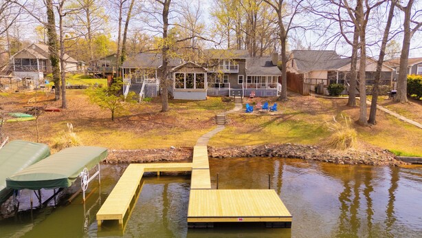A residential area with a dock extending into a pond, surrounded by houses and trees.