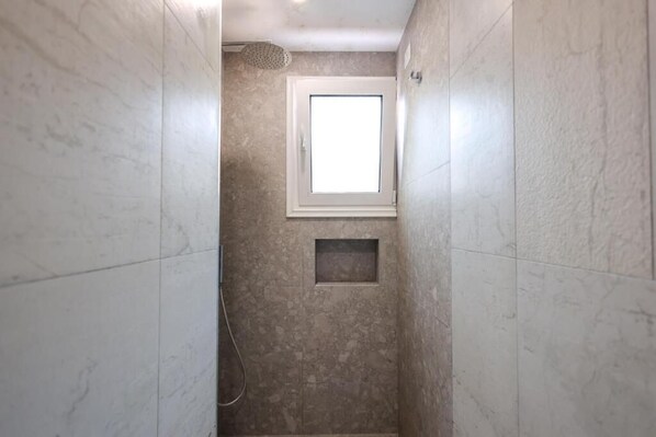 A narrow bathroom with a shower, a small window, and a recessed shelf. - Beach Guesthouse (Durres)