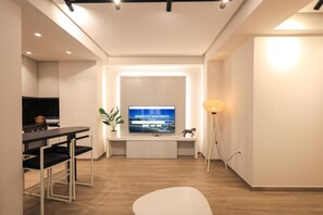 A modern living room with a flat-screen TV, a dining area, and a minimalist design. - Beach Guesthouse (Durres)