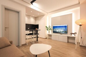 A modern living room with a sofa, a dining table, a TV, and a kitchen area. - Beach Guesthouse (Durres)