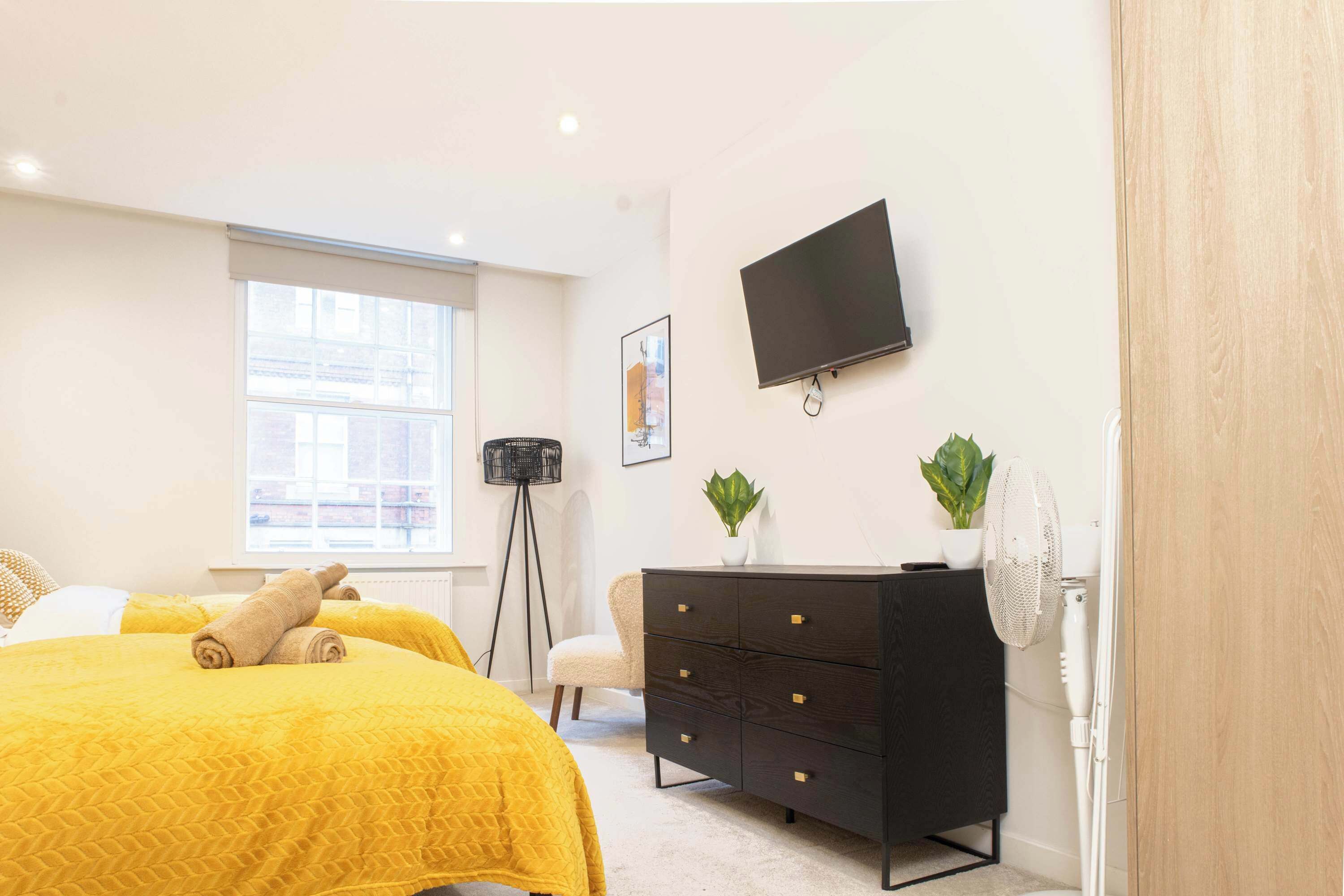 Ein Schlafzimmer mit Bett, Schminktisch, Fernseher und Fenster.