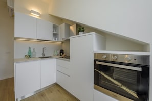 A compact kitchen with white cabinetry, a built-in oven, and a small countertop with various items. - NOVARA, 6 - In the attic with style (Milan)