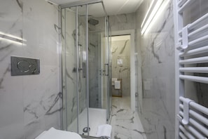 A modern bathroom with a glass-enclosed shower, marble walls, and a white towel rack. - NOVARA, 6 - In the attic with style (Milan)