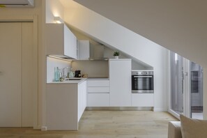 Eine moderne Küche mit weißen Schränken, einem eingebauten Backofen und einer kleinen Kochinsel mit einer Pflanze.