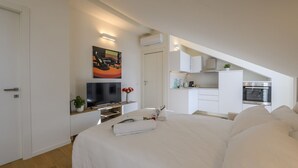 Une chambre moderne avec un grand lit, une télévision et un coin cuisine en arrière-plan.