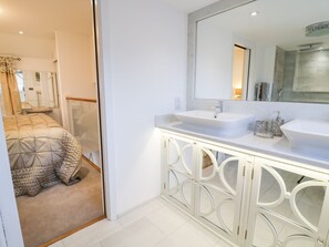 A modern bathroom with a large mirror, two sinks, and a glass-enclosed cabinet. - 8 Crown Lane (Conwy)