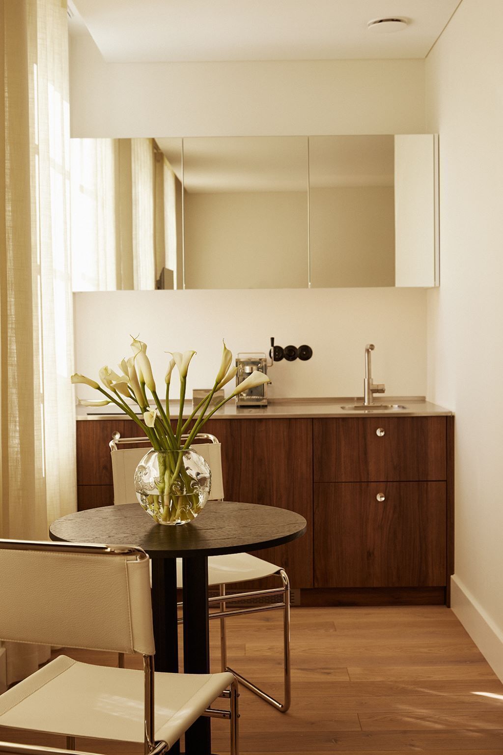 Eine moderne Küche mit Holzausstattung, einem runden Esstisch mit Blumenvase und einem Stuhl.