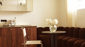 Una sala de estar moderna con un aparador de madera, una mesa redonda con un florero, un sofá y una silla.