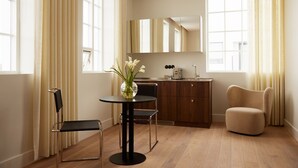 Una cocina moderna con armarios de madera, una mesa redonda con sillas y un sillón color crema.