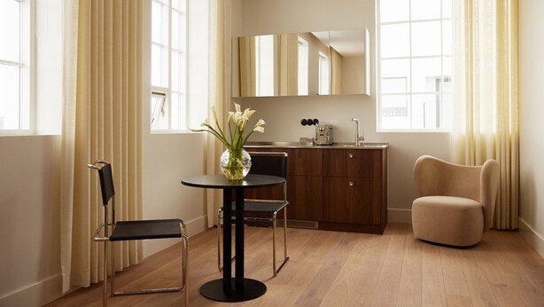 Una cocina moderna con armarios de madera, una mesa redonda con sillas y un sillón color crema.