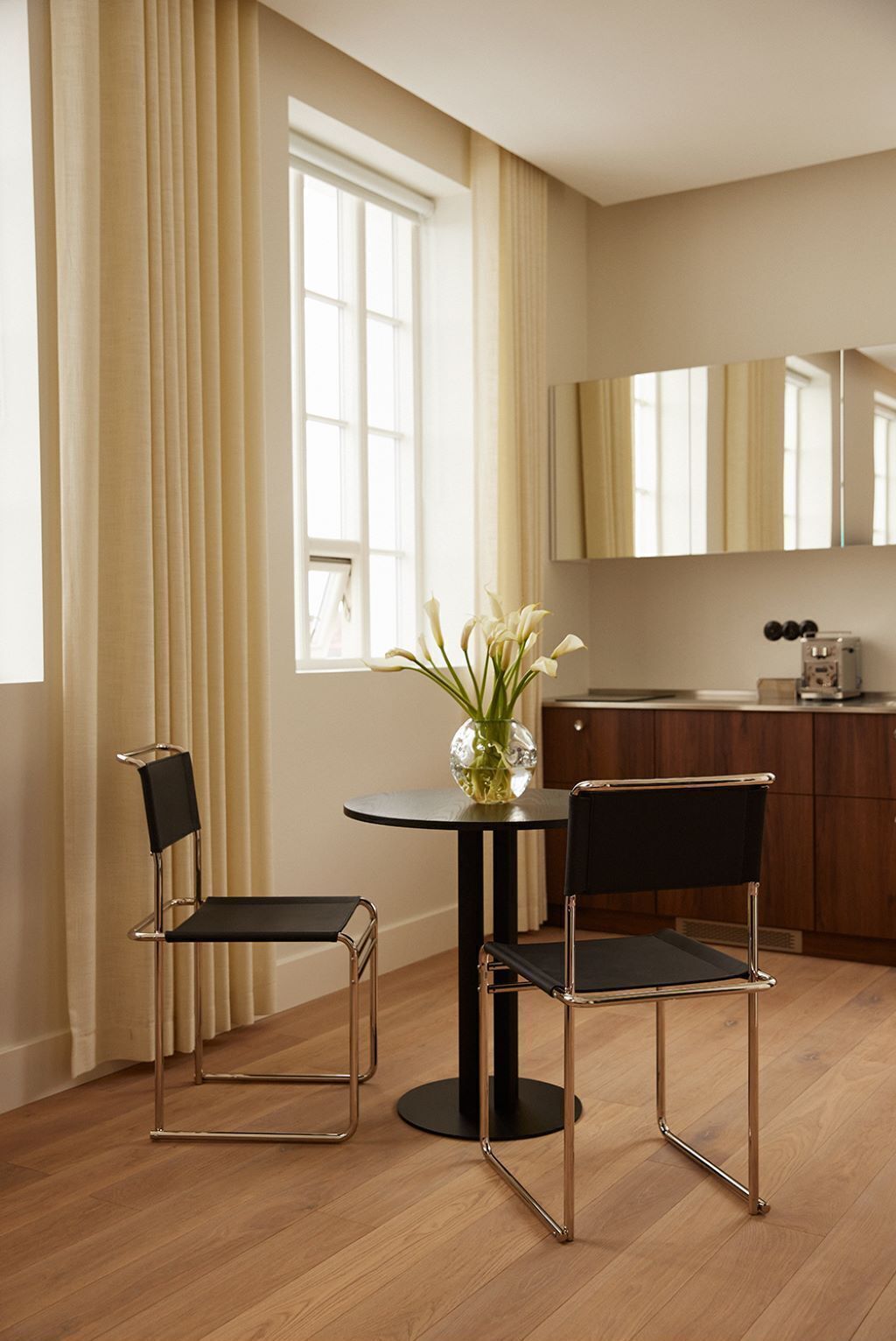 Una cucina moderna con un tavolo rotondo, due sedie e un vaso con fiori.