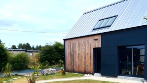 A modern building with a metal roof, a wooden exterior, and a well-maintained garden with rocks and plants.