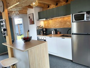 Une cuisine moderne dotée d’un îlot central, d’appareils électroménagers en acier inoxydable et d’un plafond en bois.