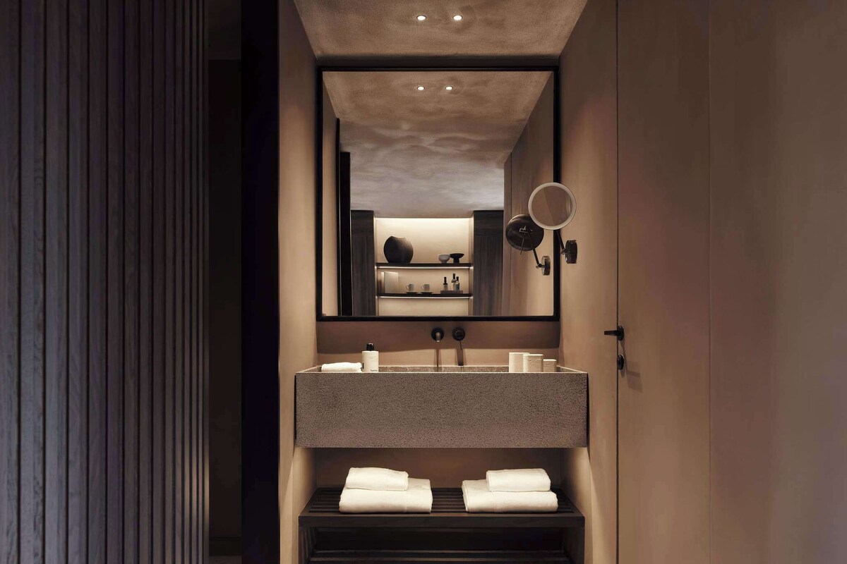 A modern bathroom with a built-in sink, a mirror, and a towel rack.