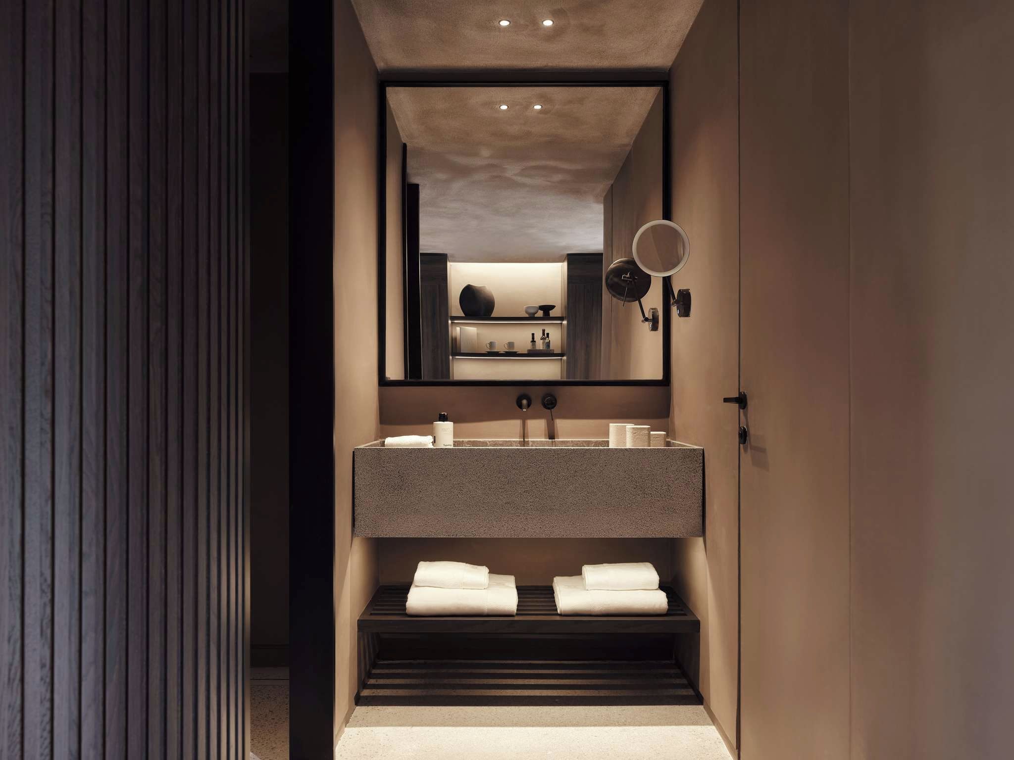 A modern bathroom with a built-in sink, a mirror, and a towel rack.