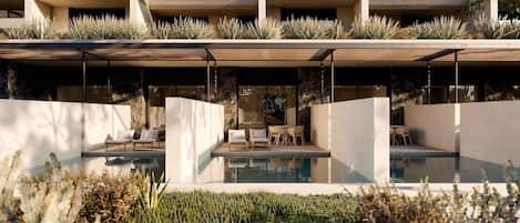 Un edificio moderno con zona de piscina, mobiliario exterior y fachada de piedra.