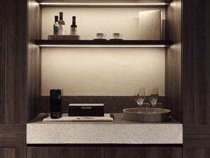 A modern kitchen with a built-in wine rack, a coffee machine, and a tea kettle. - Nirema Hotel & Spa Samos - Mgallery Collection (Samos)