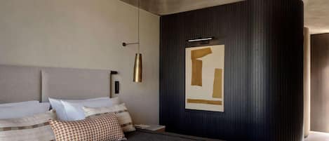 A modern bedroom with a large bed, a wall-mounted light fixture, and a decorative panel.