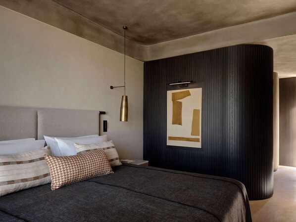 A modern bedroom with a large bed, a wall-mounted light fixture, and a decorative panel. - Nirema Hotel & Spa Samos - Mgallery Collection (Samos)