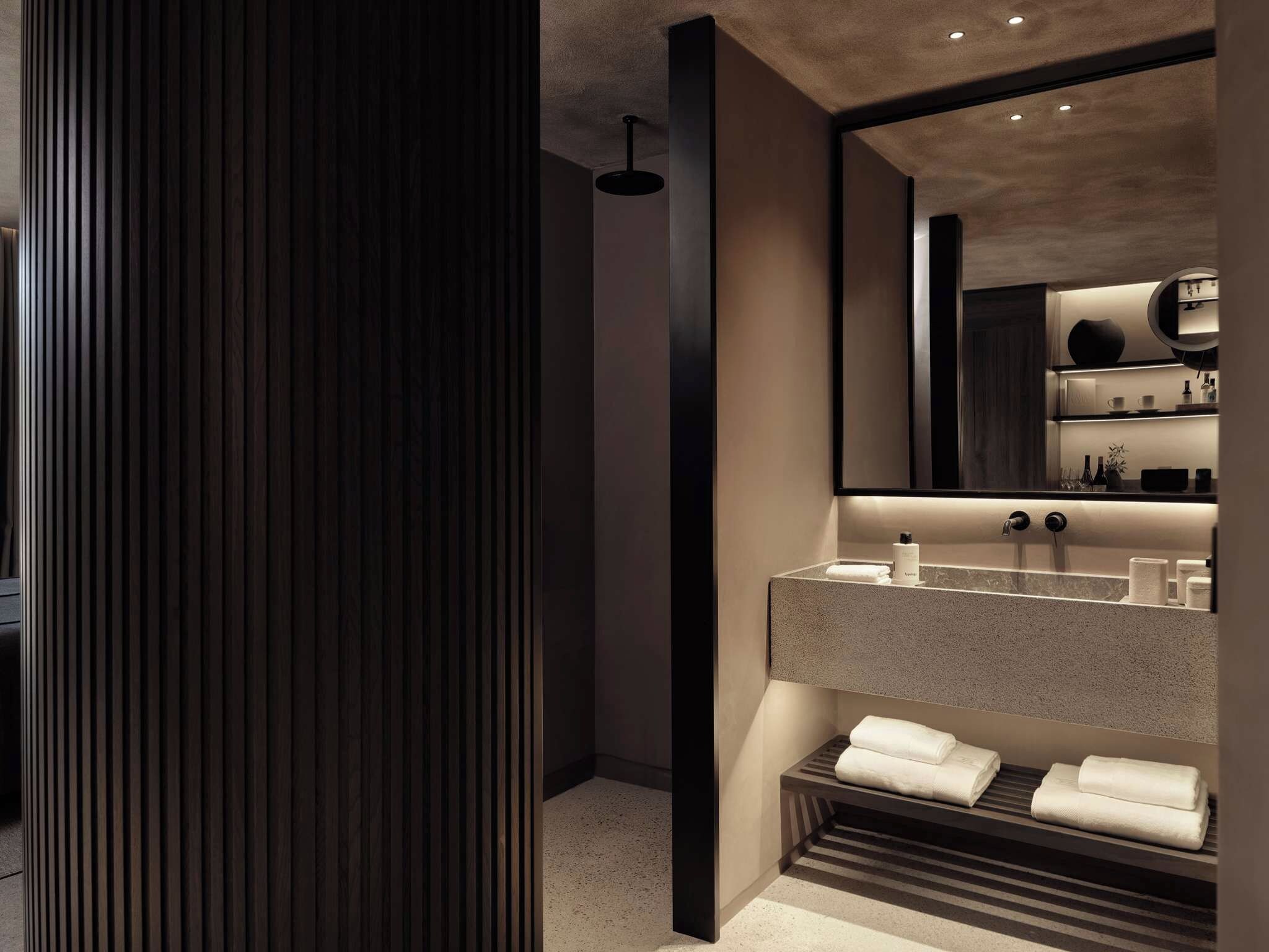 Un baño moderno con un espejo grande, un lavamanos empotrado y un perchero para toallas.