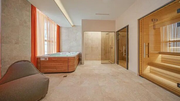 Un baño moderno con una bañera de madera, zona de ducha y un espejo grande.