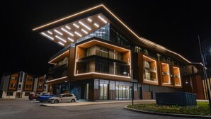 A modern building with a flat roof, large windows, and a parking area with cars. - Hotel Complex SamElyon (Samokov)