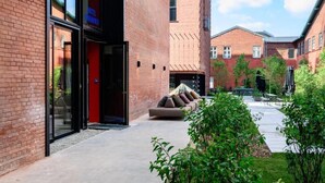 L’entrée d’un hôtel avec une façade en verre, une porte rouge et une façade en briques.