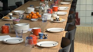 Une longue table à manger, entourée de chaises, avec des assiettes, des tasses et une variété de plats.