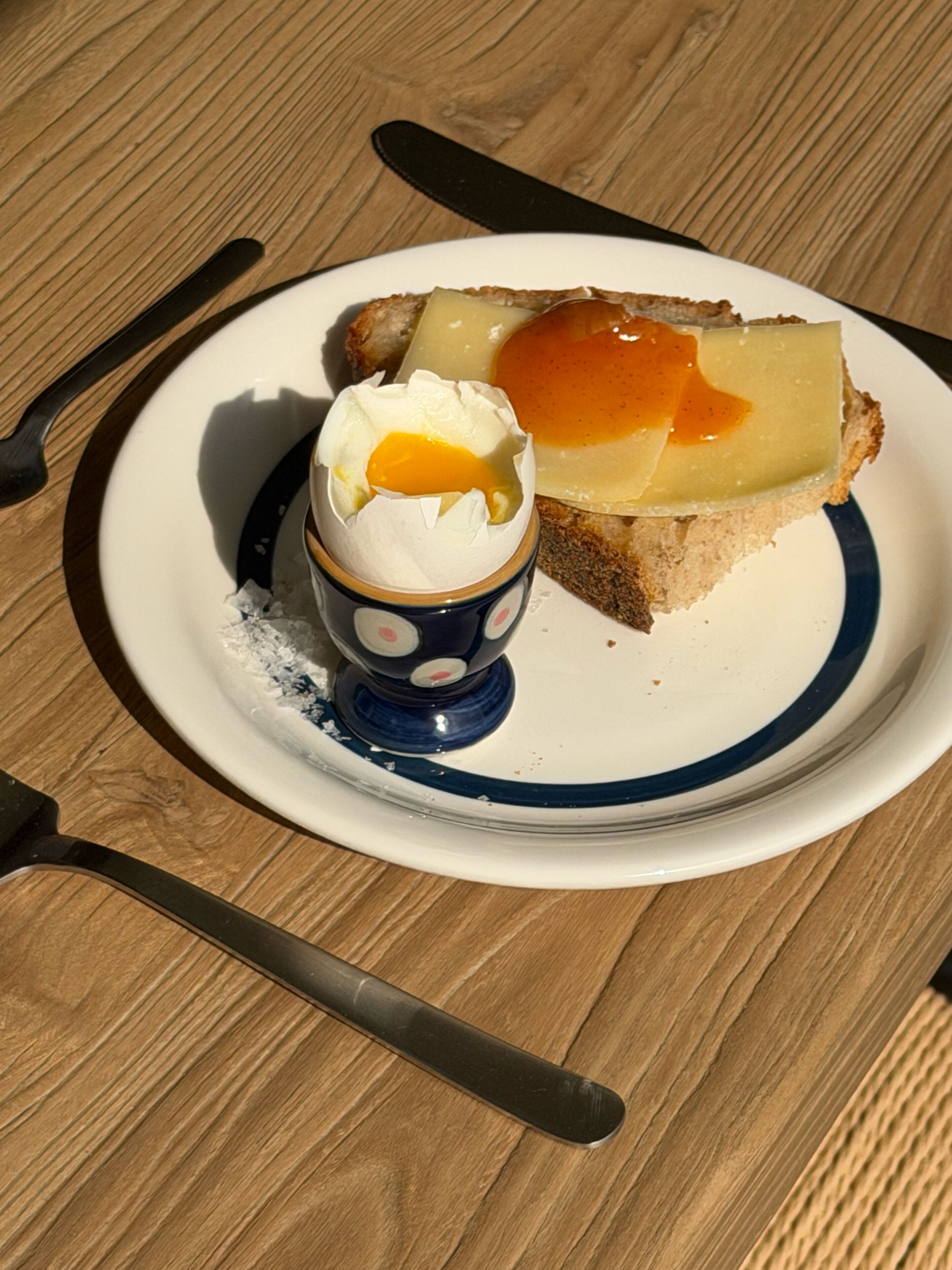 Ein Teller mit einer Scheibe Toast, belegt mit Käse und einem pochierten Ei, dazu eine kleine Tasse Kaffee.