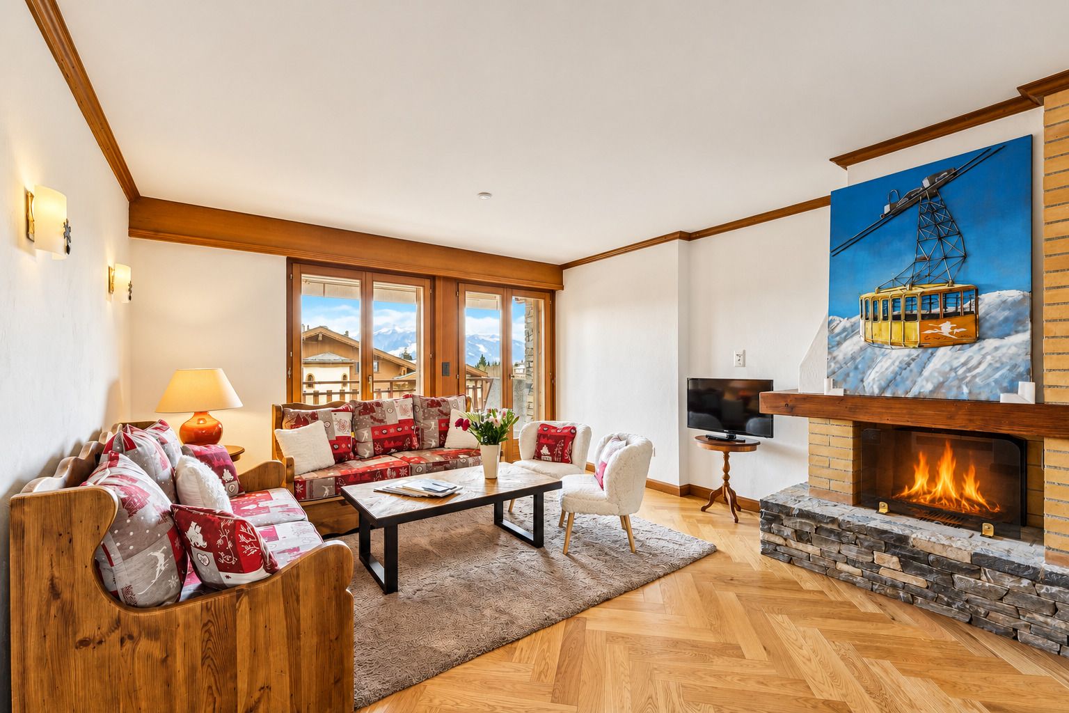 Un salón amplio con chimenea, televisión y un ventanal con vistas a un paisaje montañoso.