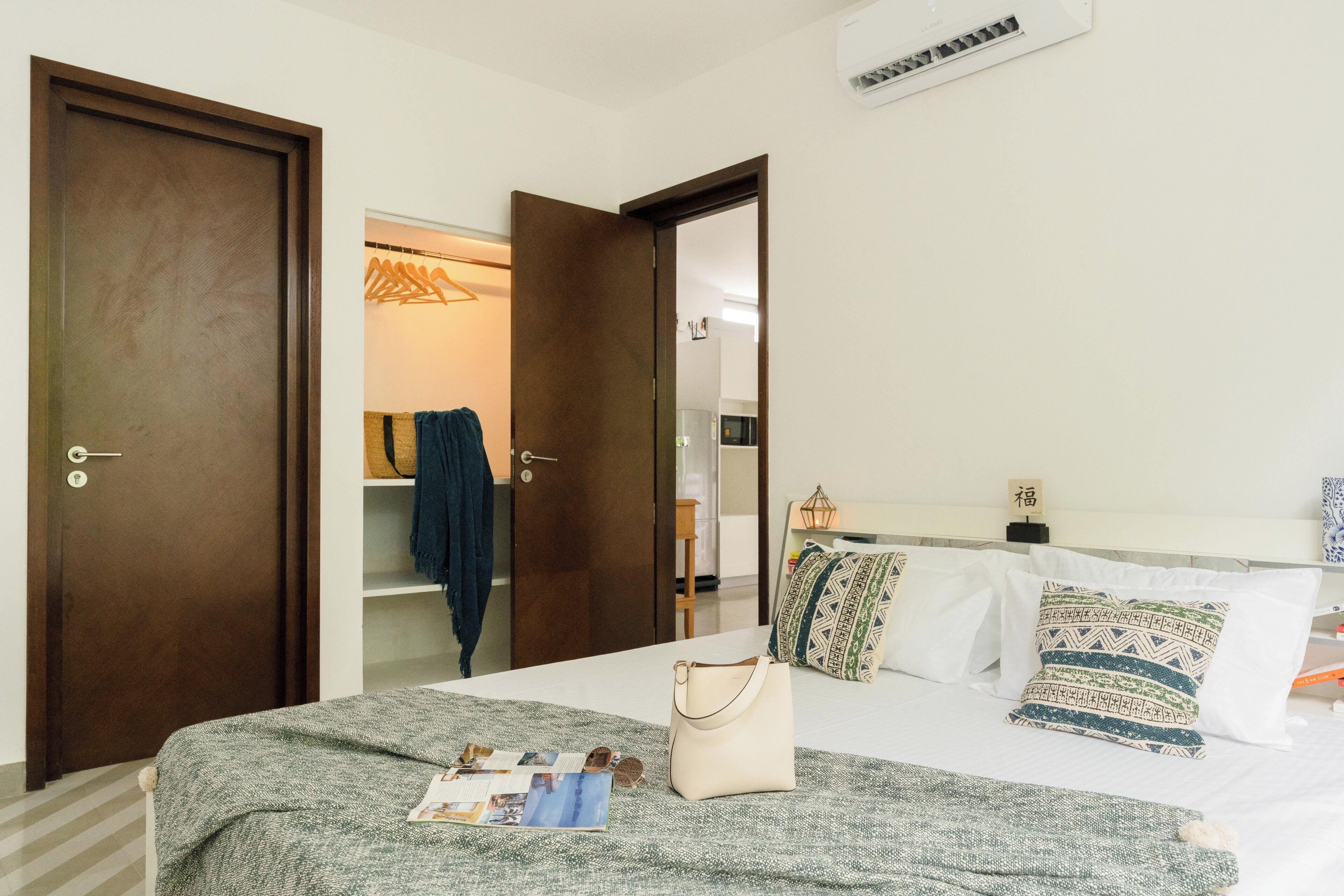 A hotel room with a bed, a wardrobe, and a door leading to a bathroom.