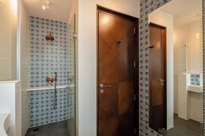 Un bagno con piastrelle decorate, una porta in legno, un box doccia in vetro e uno specchio.