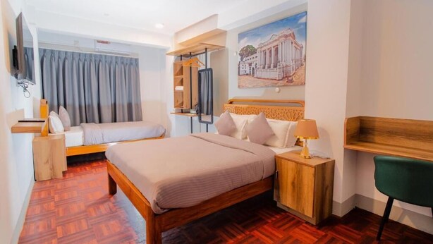 Une chambre d’hôtel avec un lit, un bureau, une chaise, une télévision et un tableau au mur.