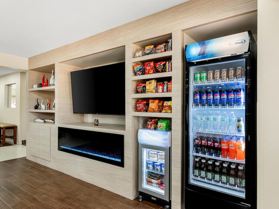 Uma sala de estar moderna com televisão de tela plana, aquário embutido e máquina de venda automática abastecida com lanches e bebidas.