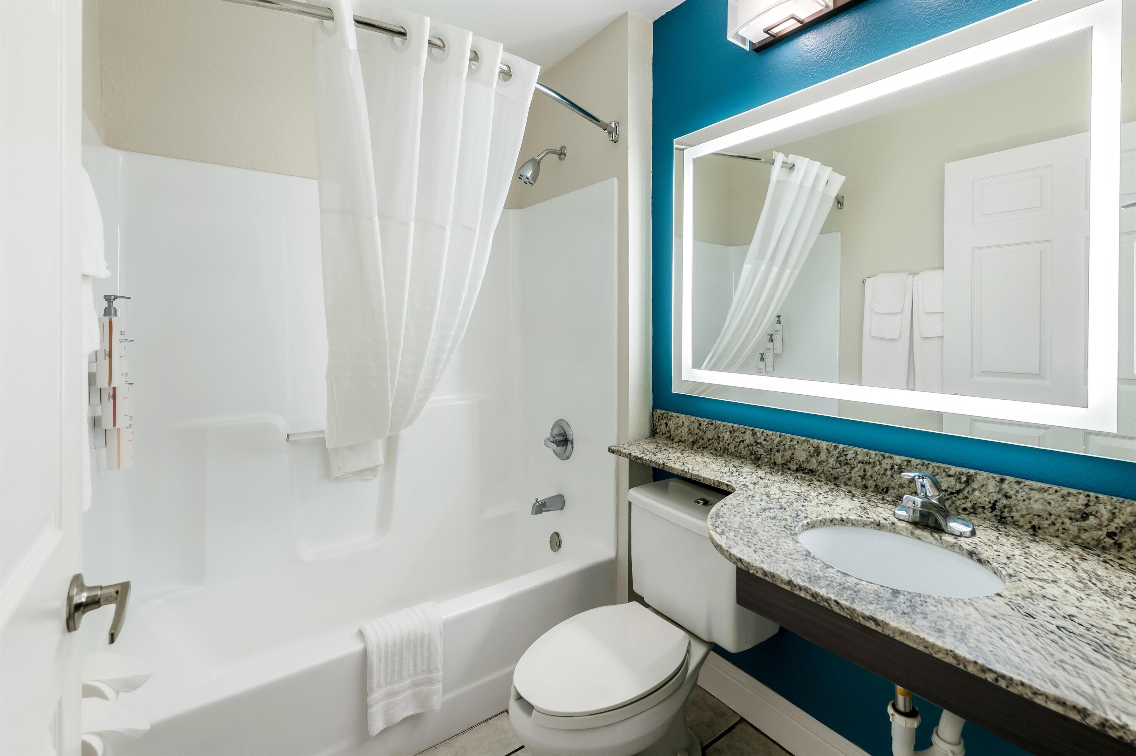 Un baño con bañera, inodoro, lavamanos y cortina de ducha.
