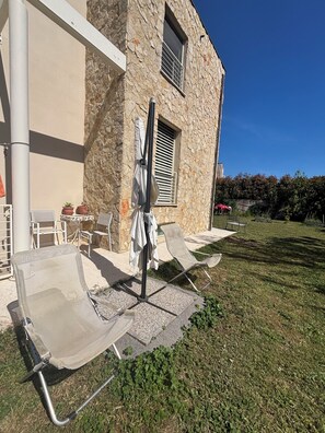 A stone building with outdoor seating, including lounge chairs and a table. - The Ship Leaf, in nature by the sea (Livorno)