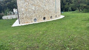 Un bâtiment en pierre doté d’une fenêtre de forme circulaire, entouré d’une pelouse bien entretenue.