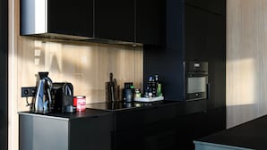 A modern kitchen with black cabinets, a stainless steel countertop, a coffee maker, a kettle, and a can of tomato paste. - Modern Design House With Sauna 'arduenna Silva' (La Roche-en-Ardenne)