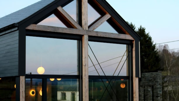 A modern building with large windows, a wooden facade, and a stone wall in the background. - Modern Design House With Sauna 'arduenna Silva' (La Roche-en-Ardenne)