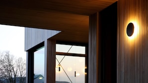 A modern building interior with wooden paneling, large windows, and a circular light fixture. - Modern Design House With Sauna 'arduenna Silva' (La Roche-en-Ardenne)