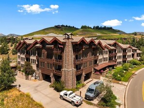 Eine mehrstöckige Lodge mit einem Stein-Turm, Balkonen und einem Parkplatz.