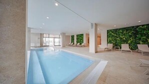 Une piscine intérieure dotée de chaises longues et d’un mur végétal.