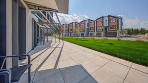 Un bâtiment moderne doté d’un espace extérieur abrité avec des sièges et d’une pelouse bien entretenue.