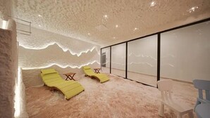 Une pièce avec un plafond à motifs, deux fauteuils jaunes, une petite table et une grande fenêtre.